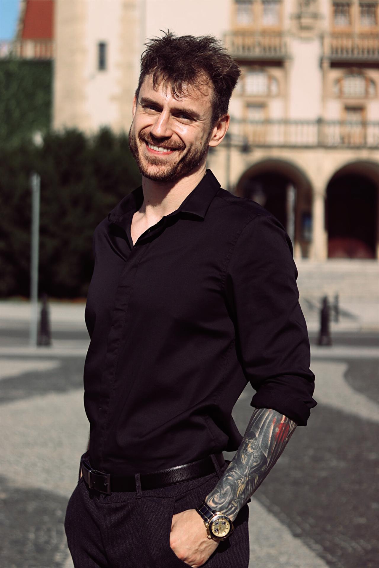 Adam Miszczak, Senior SEO and AI Search specialist, smiling in a black shirt outdoors.