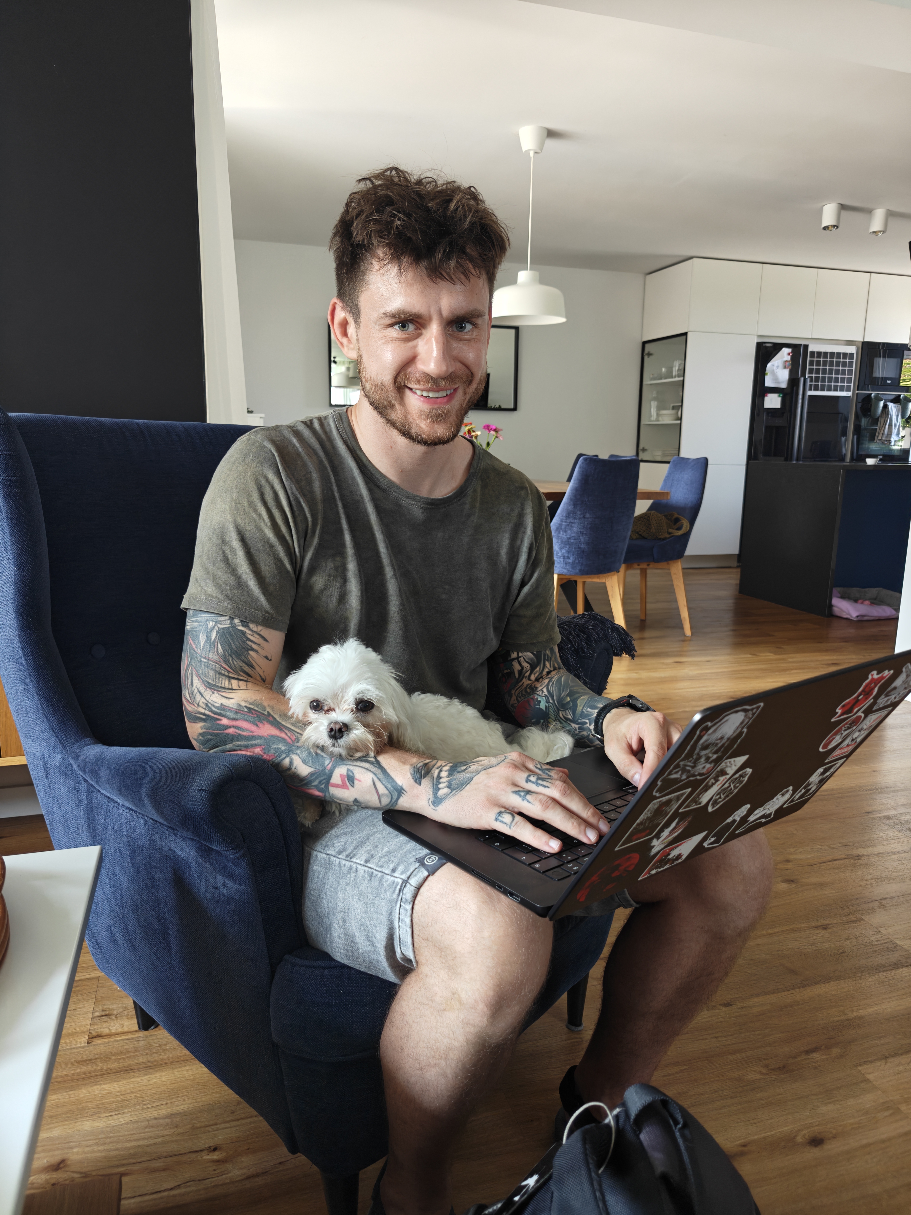 Adam Miszczak, SEO and GEO specialist, working at a laptop at home with a small white dog beside him.