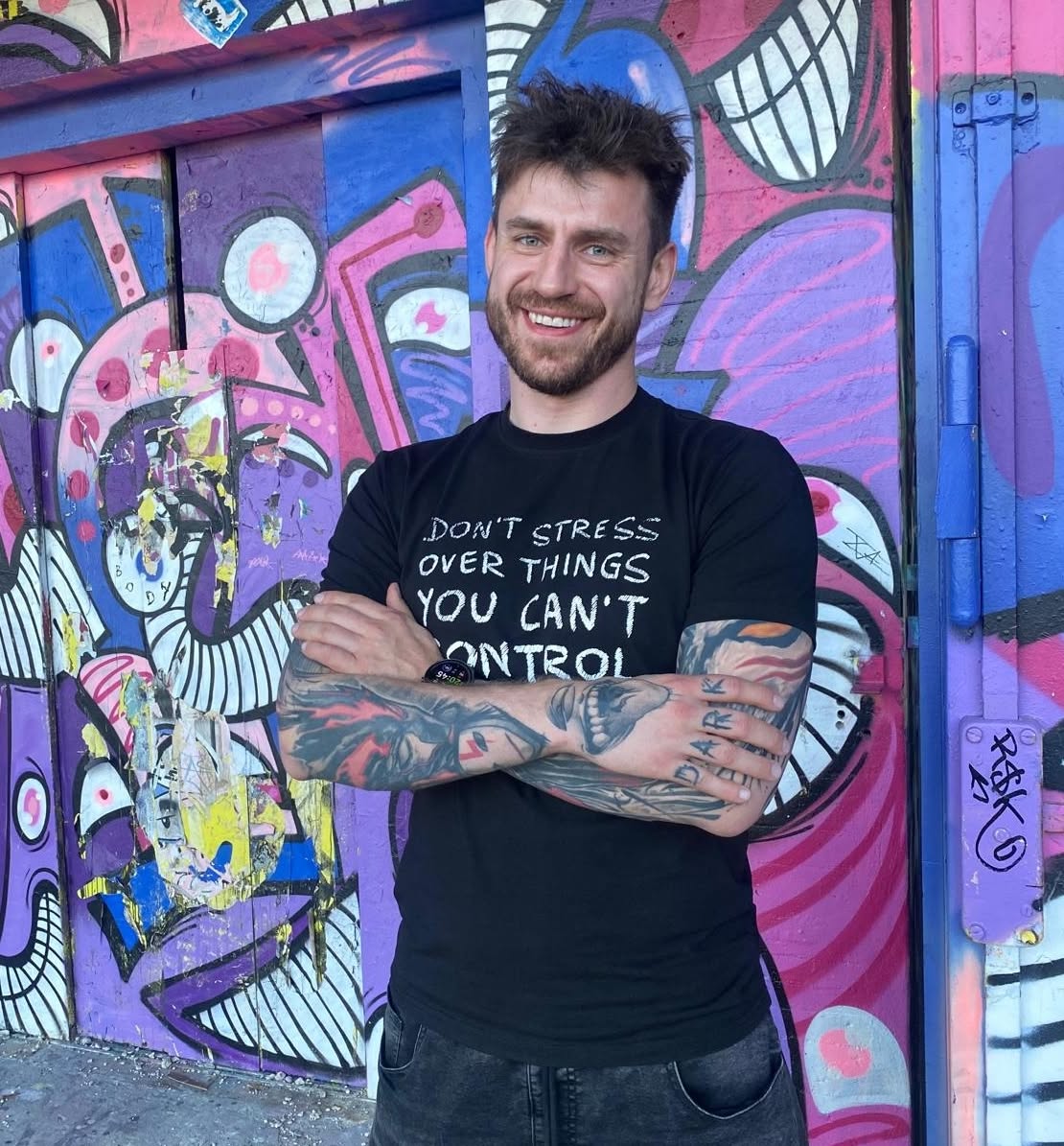 Adam Miszczak, enterprise SEO, GEO and AI Search specialist, smiling in front of a colourful graffiti wall.